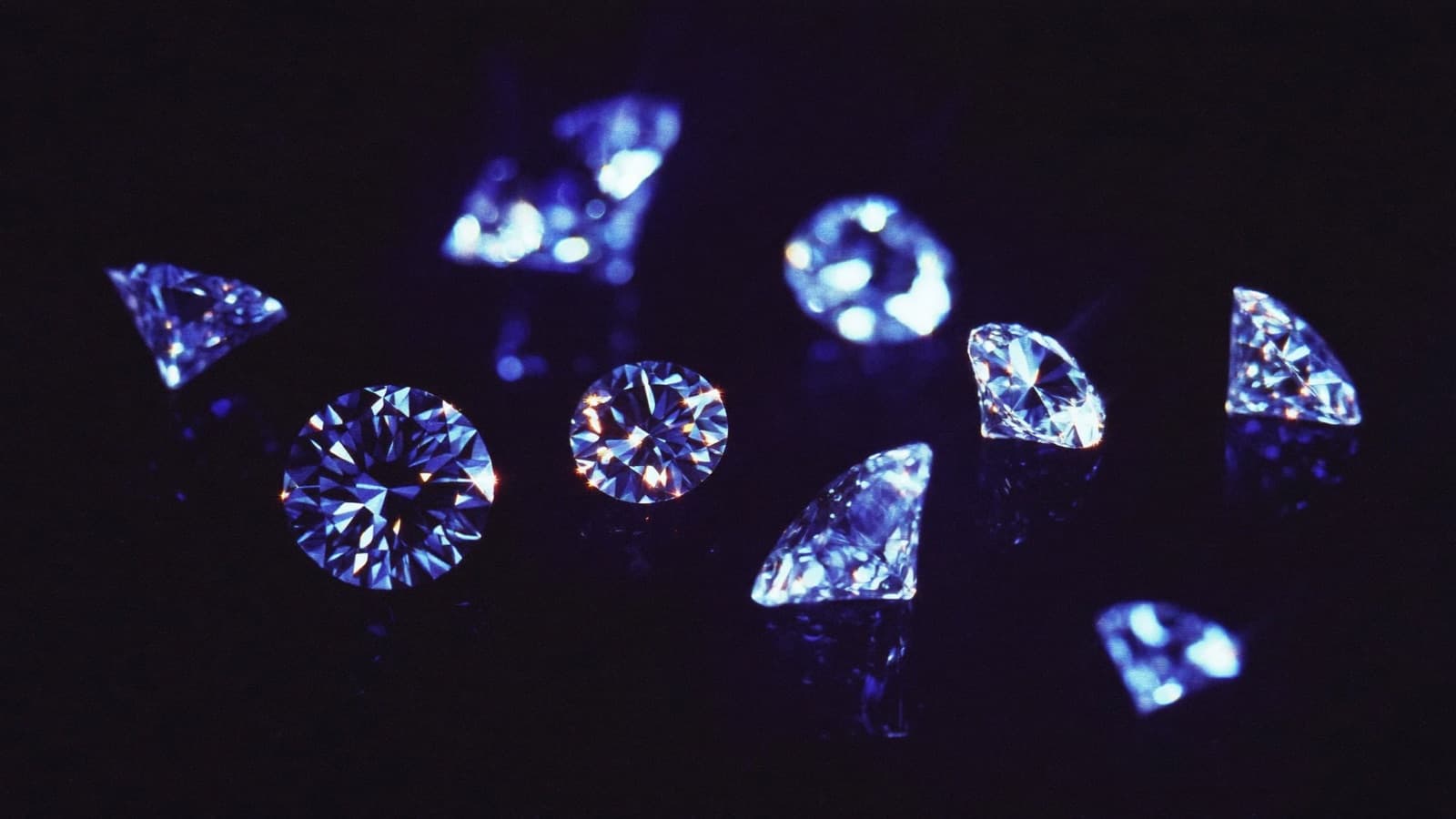 Macro photograph of diamonds glittering violet and cyan on black glass