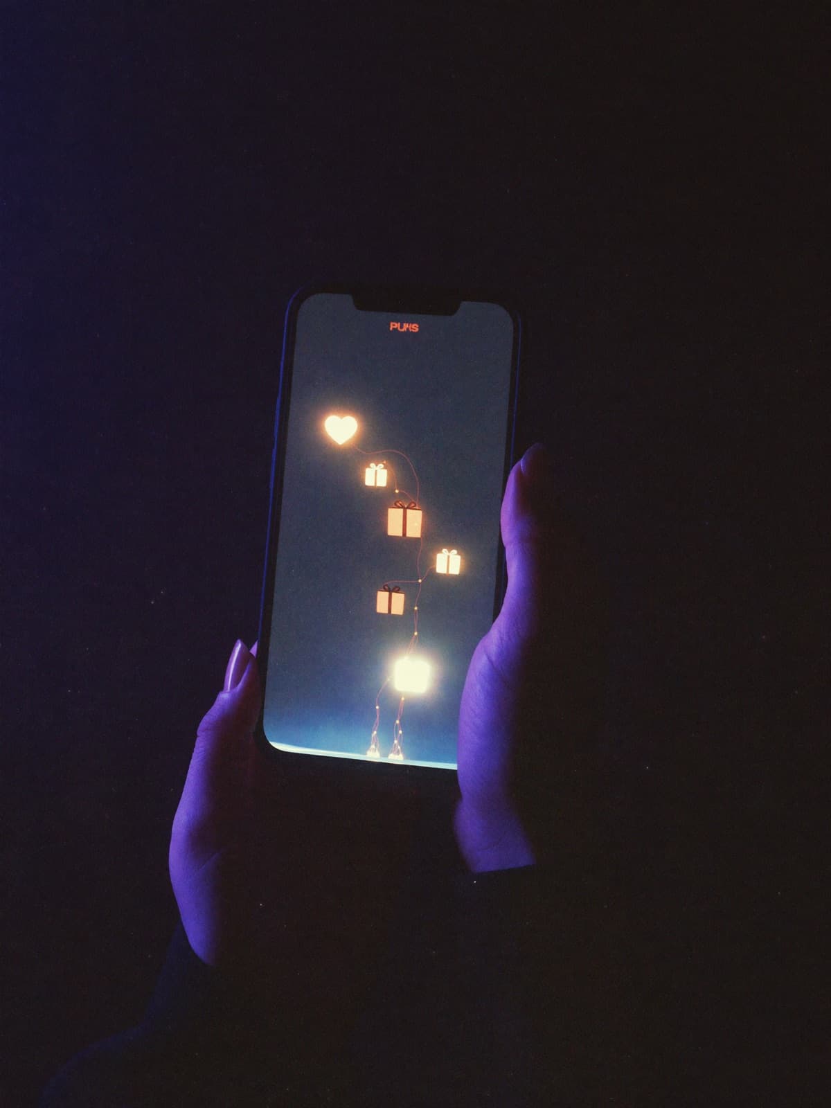 Hands holding a phone with luminous gift and heart icons rising from the screen